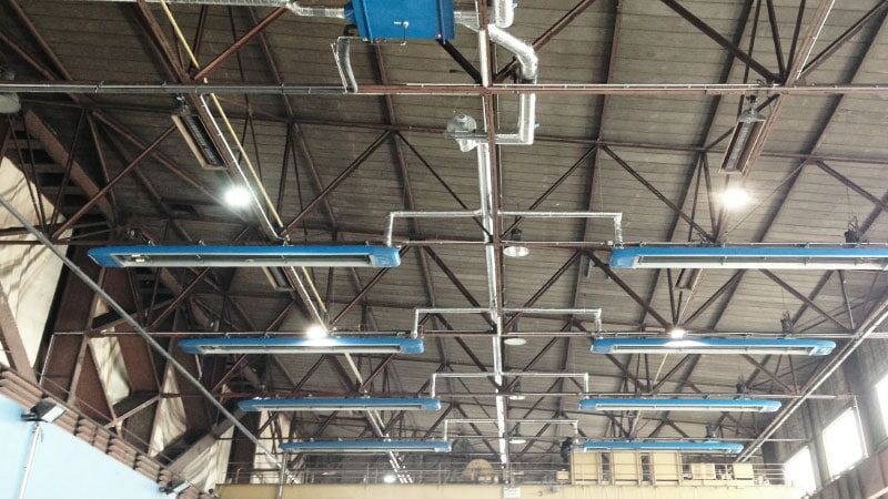 Industriehalle mit Beleuchtung und Rohrleitungen.