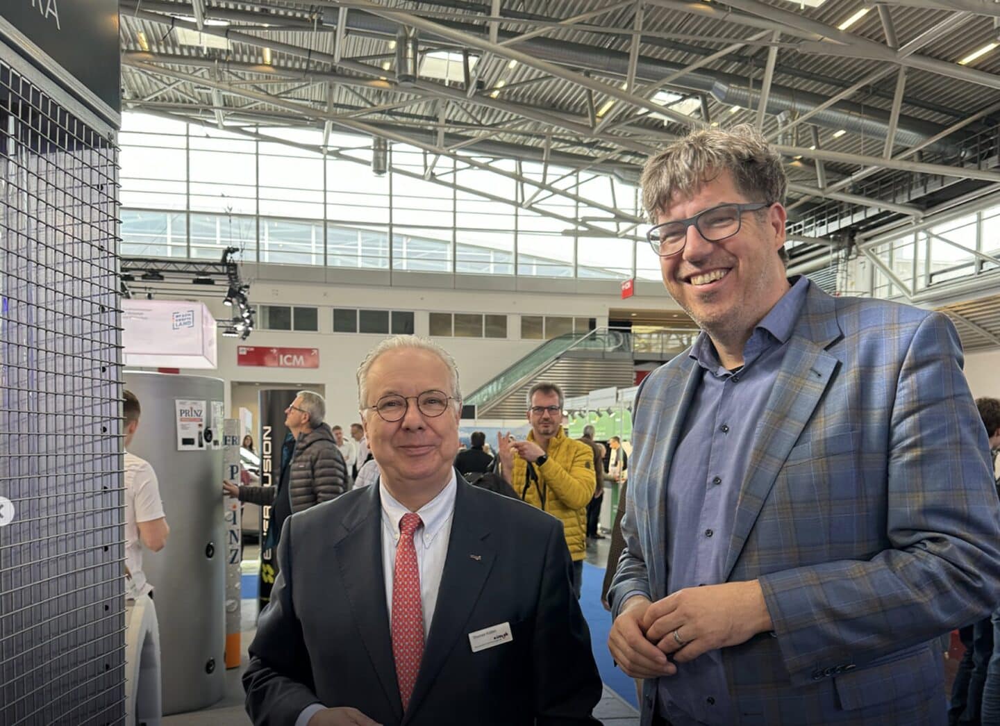 Zwei Männer auf einer Fachmesse lächelnd.