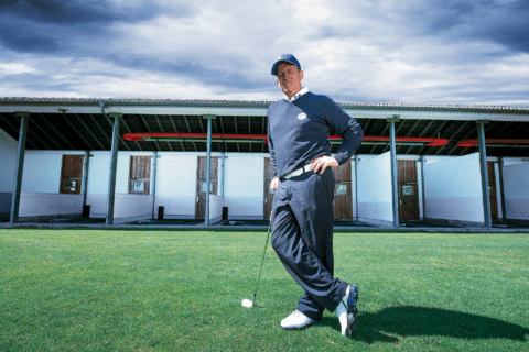 Golfer stands on practice course, day