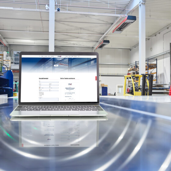 Laptop mit Webseite in einer Industriehalle.