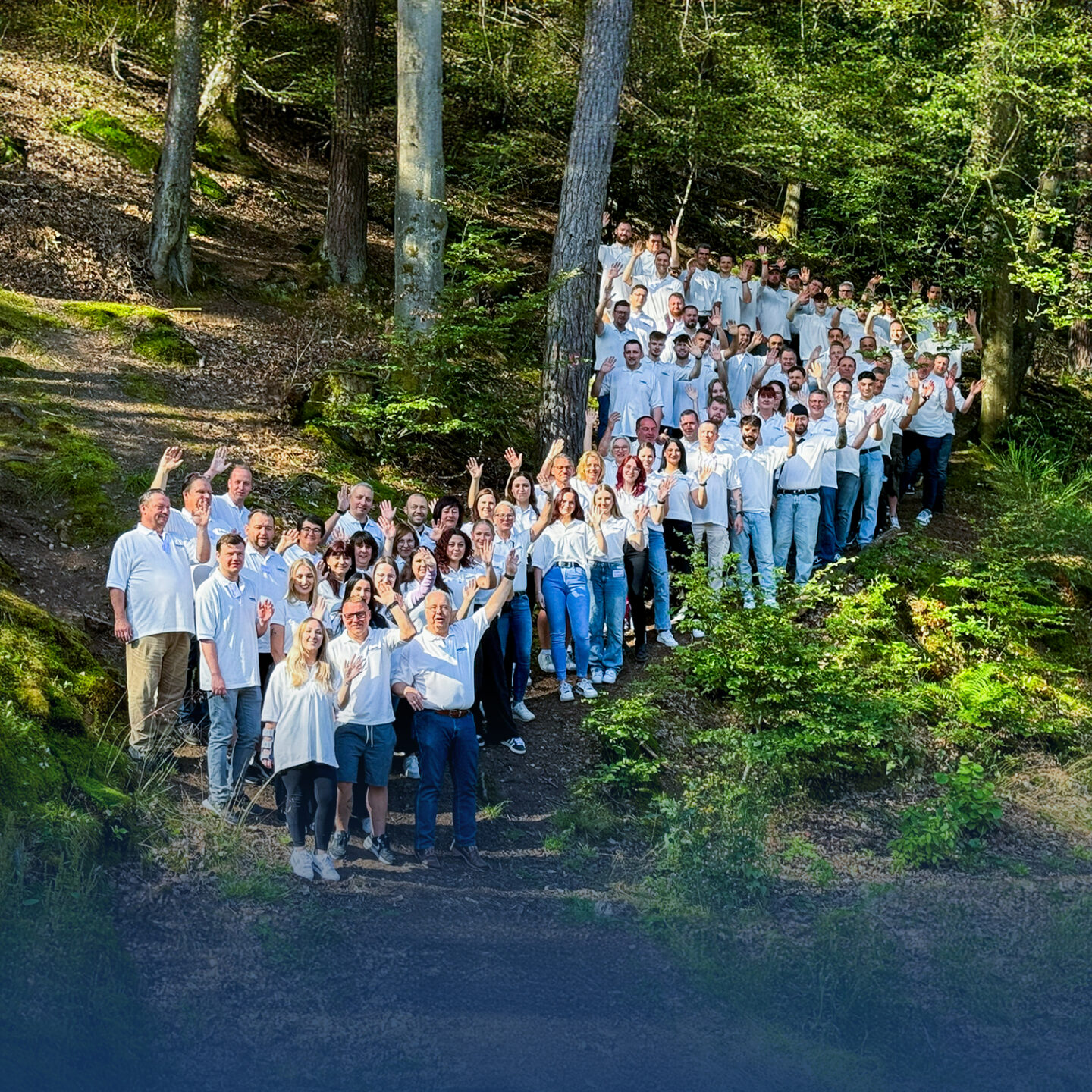 Größere Gruppe lächelt im Wald.