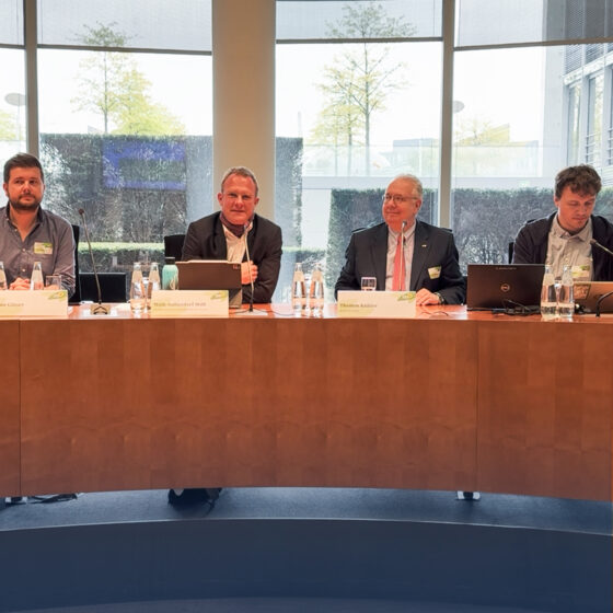 Vier Männer bei einer Konferenz mit Namensschildern.