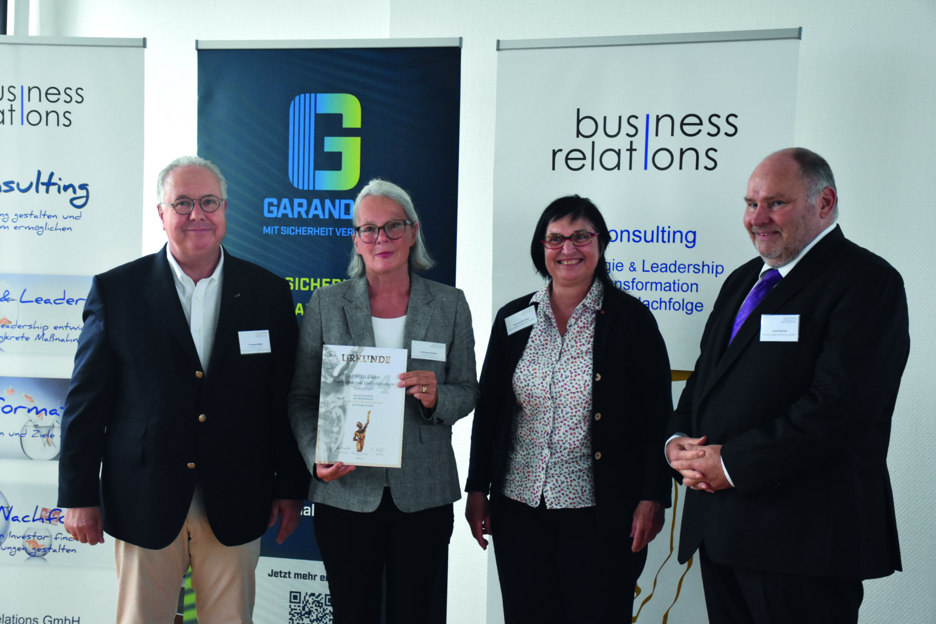 Four people receive award at business event.