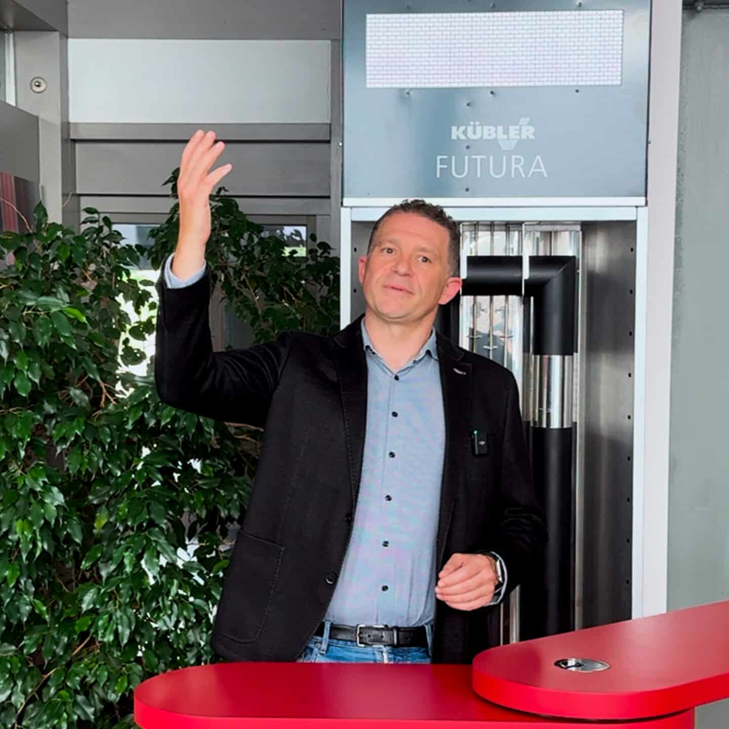 Man waving in entrance area next to red table