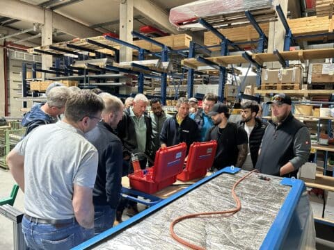 Group of men looking at tools in industrial hall