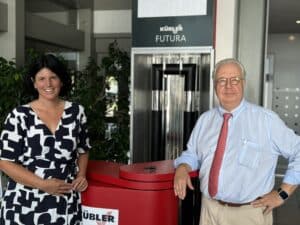 Two people stand smiling in an office environment