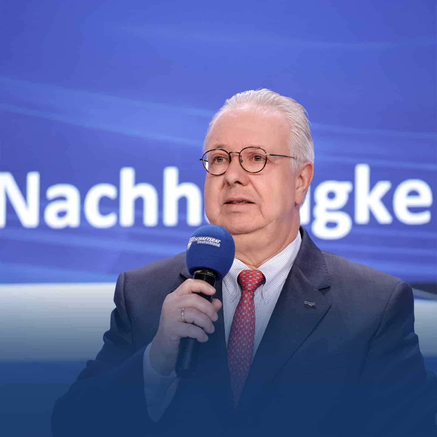 Elderly man speaking into microphone, blue background