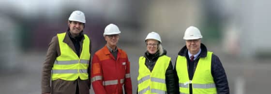 Five people in safety helmets and high-visibility vests