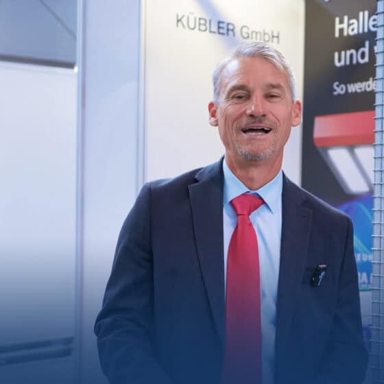 Man in suit smiles at trade fair stand