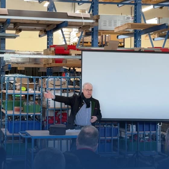 Man presents in front of an audience in a warehouse