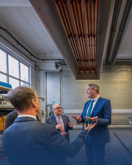 Three men are talking in a factory hall.