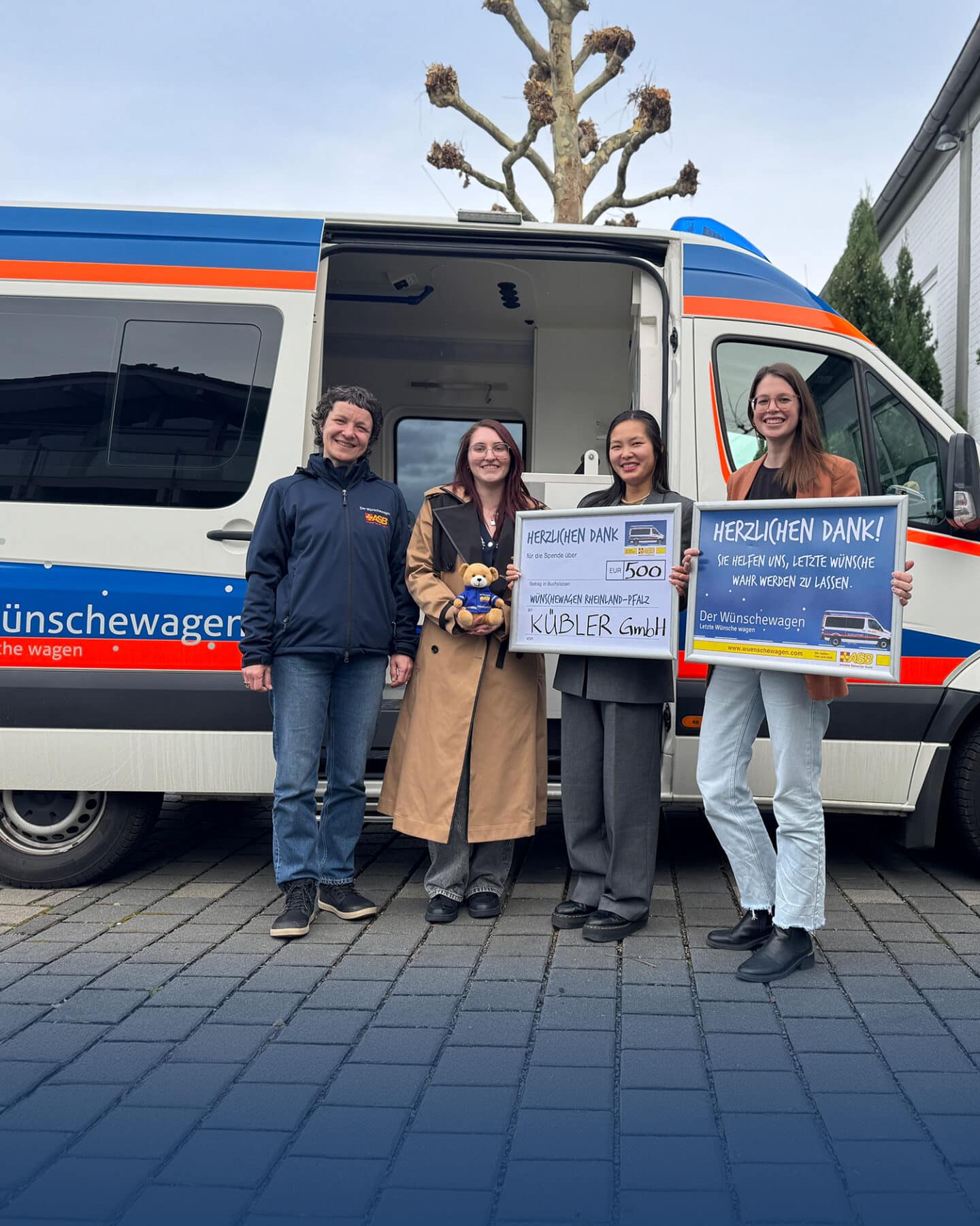 Four people present a donation in front of the wish wagon